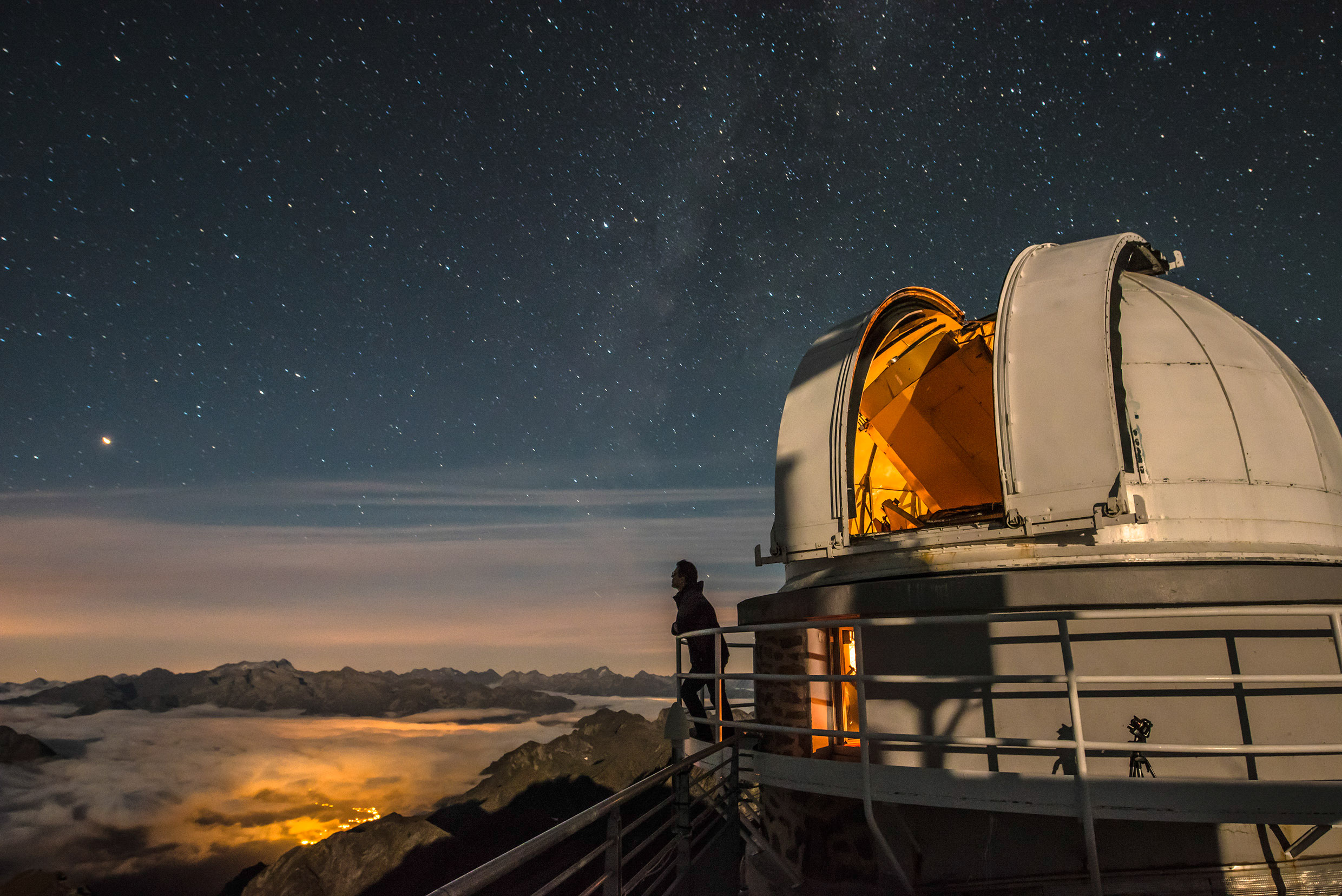 Reportage photographique "la tête dans les étoiles". David Darson contemple le panorama sur les Pyrénés devant le téléscope T1M de l'Observatoire du Pic du Midi.