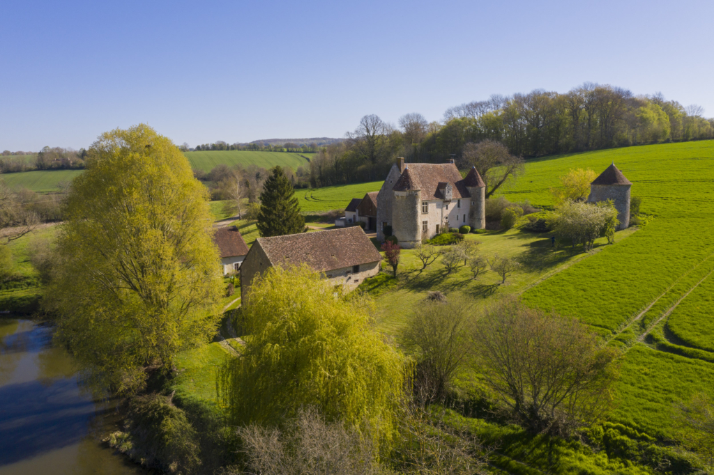Le manoir de la Manorière à Vichères. Accrochée à mi-pente d’un coteau, la Manorière domine la vallée de la Berthe, petit affluent de l’Huisne, assez fortement encaissée pour la région, à l’approche de Vichères.
Le manoir et ses communs descendent en pente douce vers trois étangs de belle taille, peut-être la survivance d’anciens viviers qui servaient de réserve à poissons.
Le manoir est une ancienne maison forte. Ses deux tours d’angle sont chacune défendue par une bretêche et des meurtrières. Une autre bretêche veille de haut sur la porte d’entrée. Une troisième tour enfin, détachée du manoir, abrite un fournil en rez-de-chaussée et un pigeonnier au-dessus.
Dès le milieu du XVIIe siècle, le manoir est laissé par ses propriétaires au fermier. Les cultures, aujourd’hui, lèchent pratiquement ses murs. Le bocage d’autrefois a cédé la place à deux immenses parcelles. L’une au-dessus des étangs, l’autre qui enserre littéralement la Manorière. Photographie extraite du projet photographique "les manoirs du Perche"